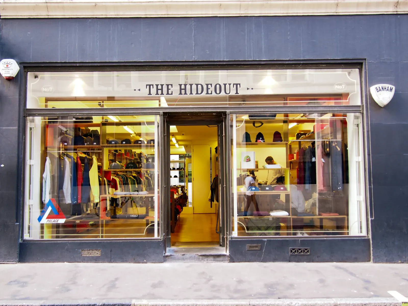 Shopfront with THE HIDEOUT lettering on the glass, clothing rails and caps visible inside