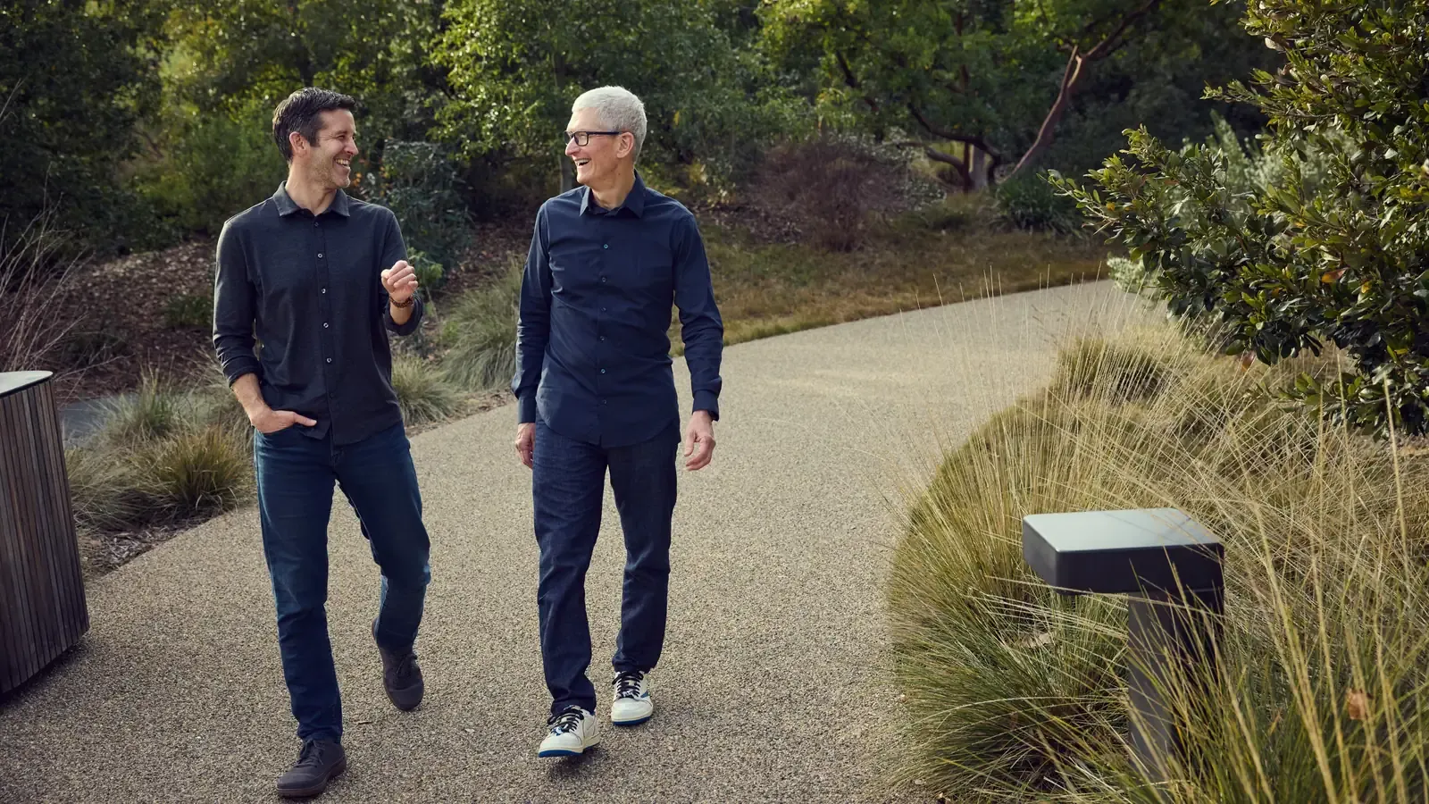 John Ternus and Tim Cook walking together through the gardens at Apple Park.