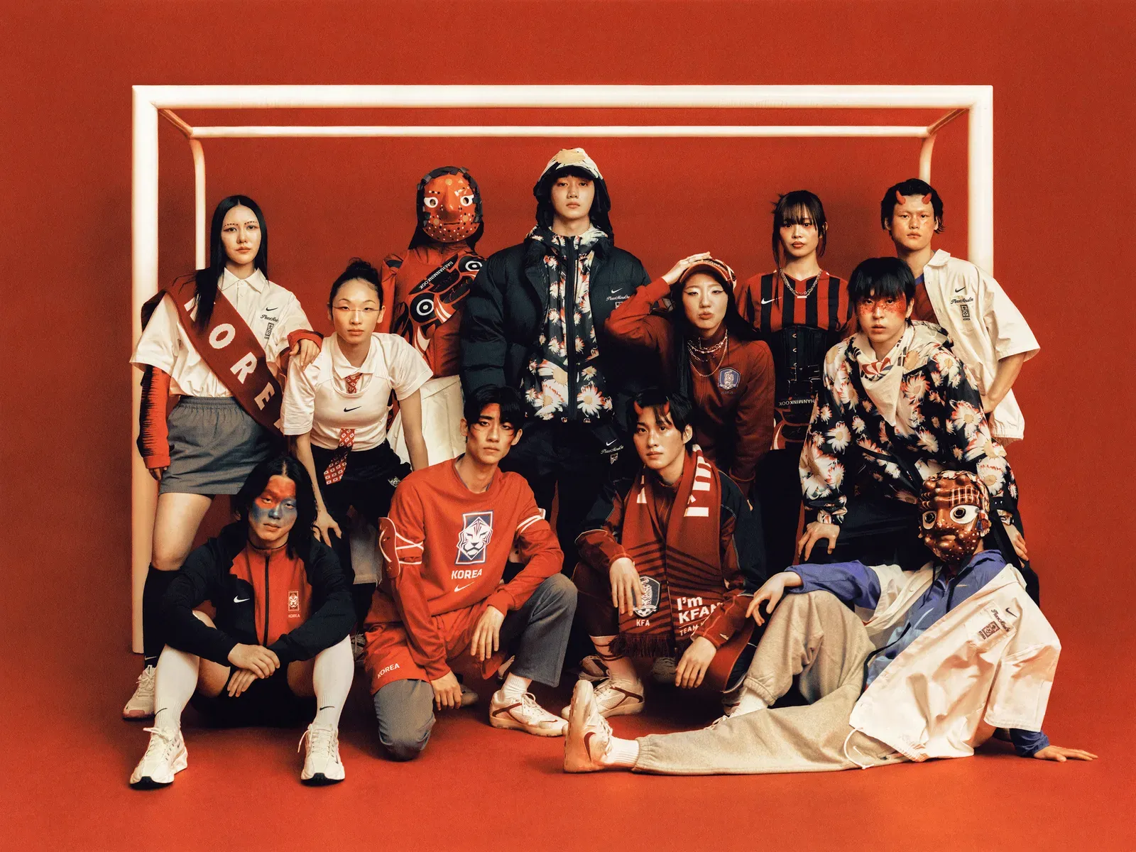 Group of young people in red and white Korea football kit and face paint posed before a white goal frame