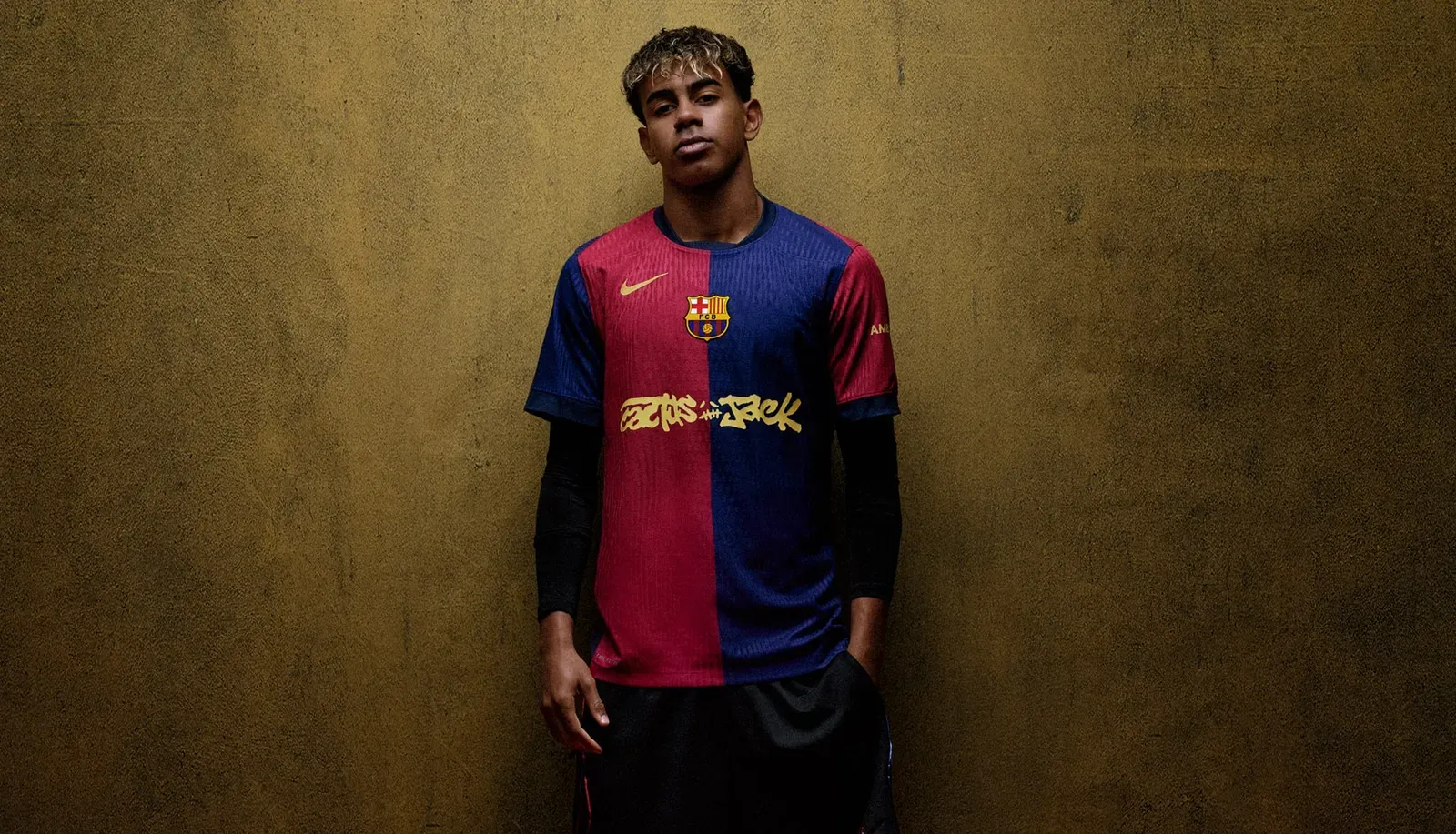 Young footballer in an FC Barcelona jersey with gold Cactus Jack lettering against a golden wall