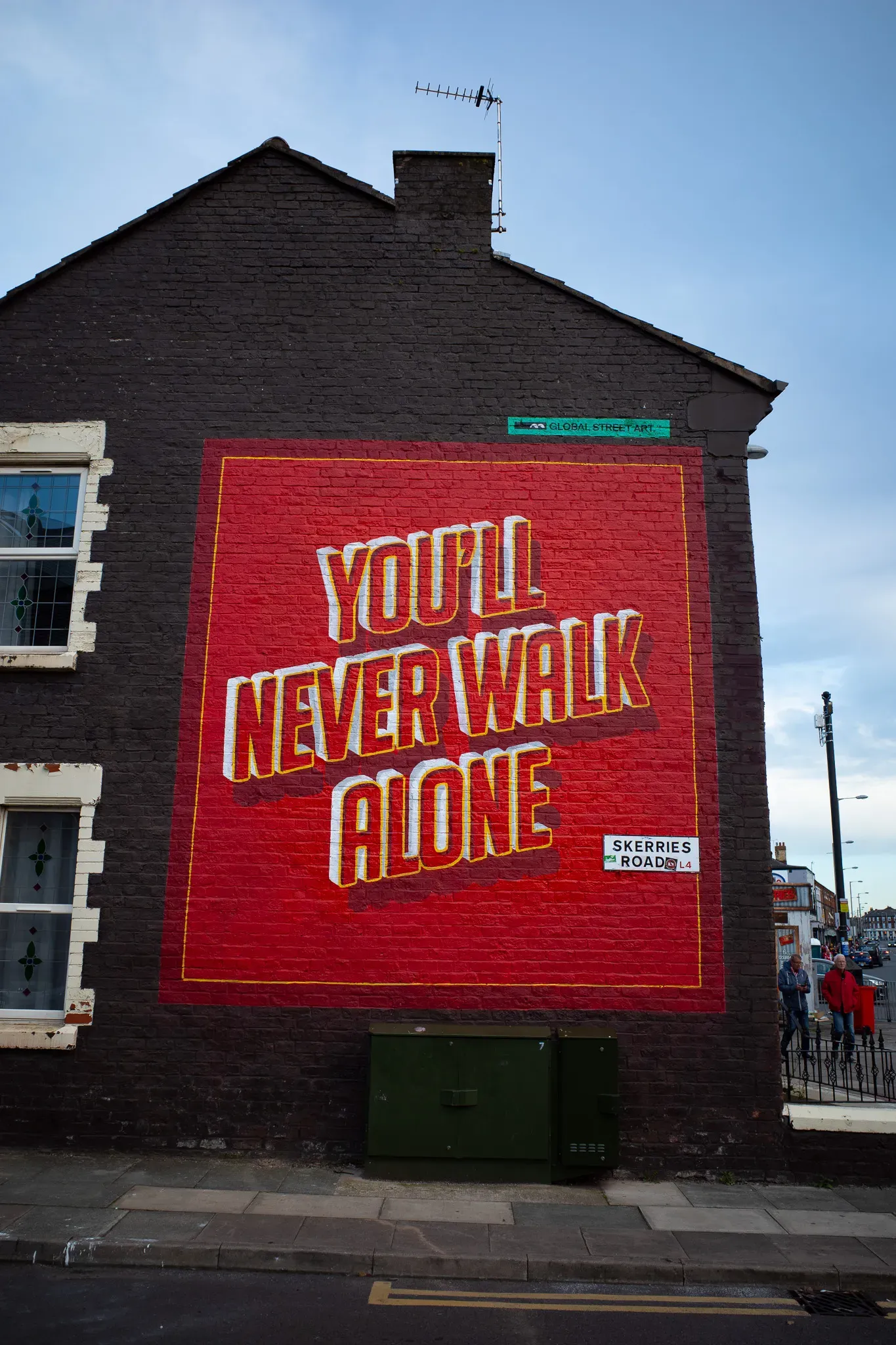 Red mural reading You'll Never Walk Alone painted on a brick house wall on Skerries Road