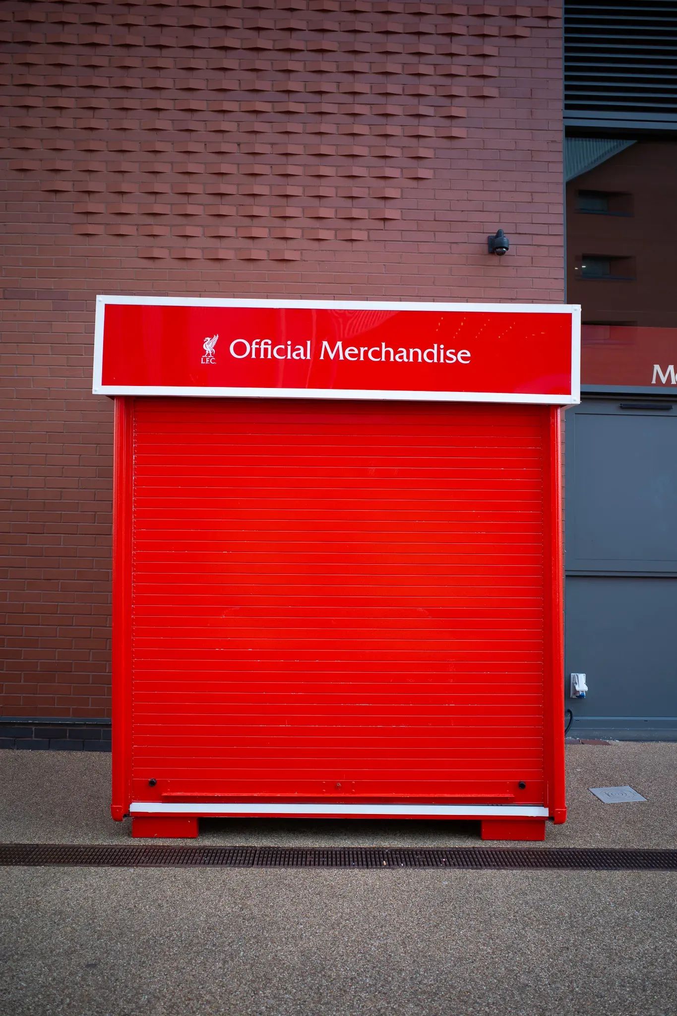 Shuttered red LFC Official Merchandise kiosk standing in front of a patterned red brick wall