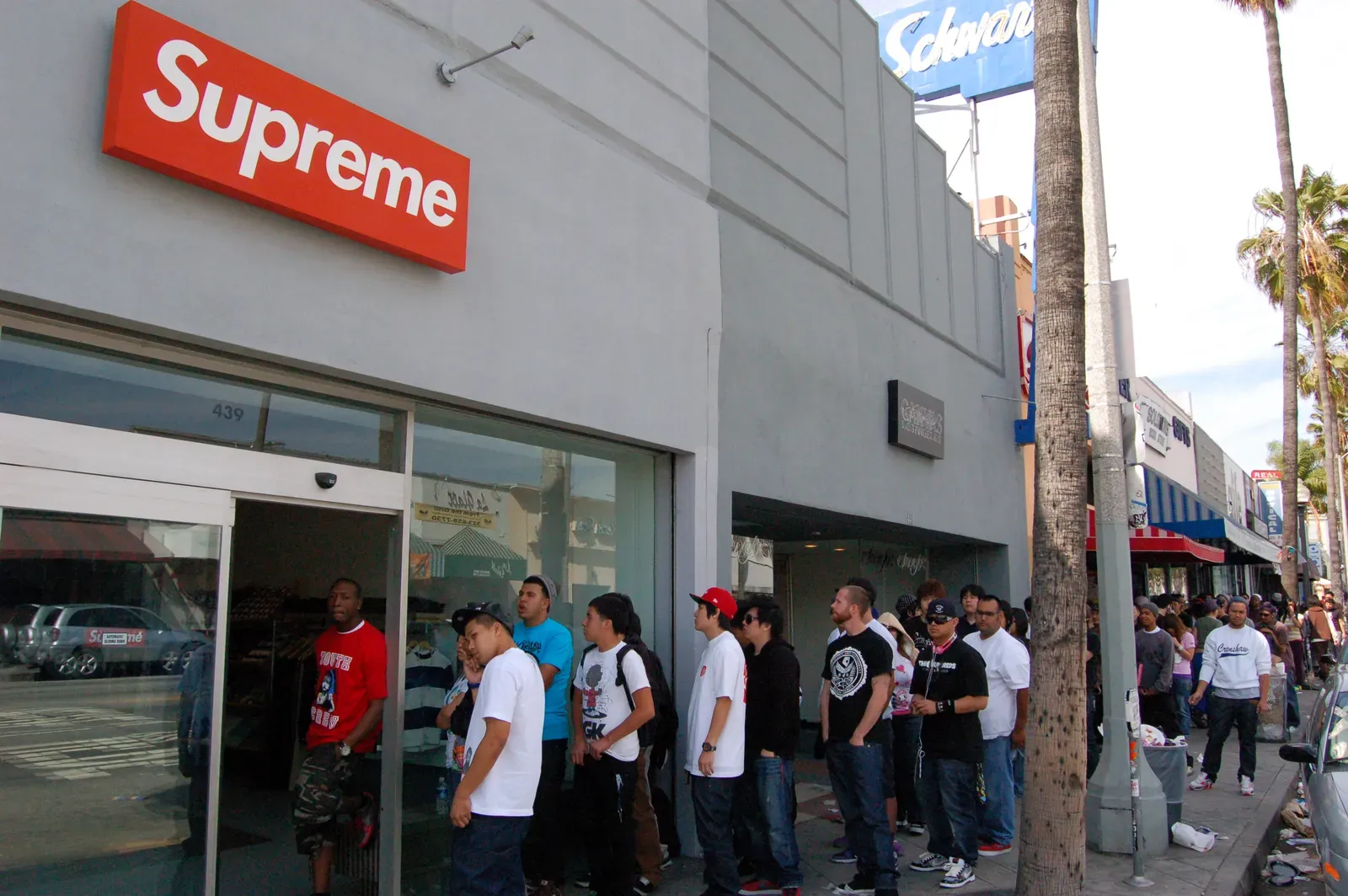 Line of young people waiting outside the Supreme store on Fairfax, under its red box logo sign