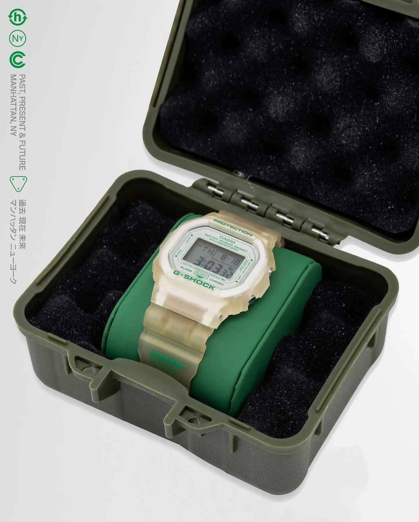 Translucent Hidden x G-Shock watch on a green cushion inside an open olive-green hard case lined with black foam