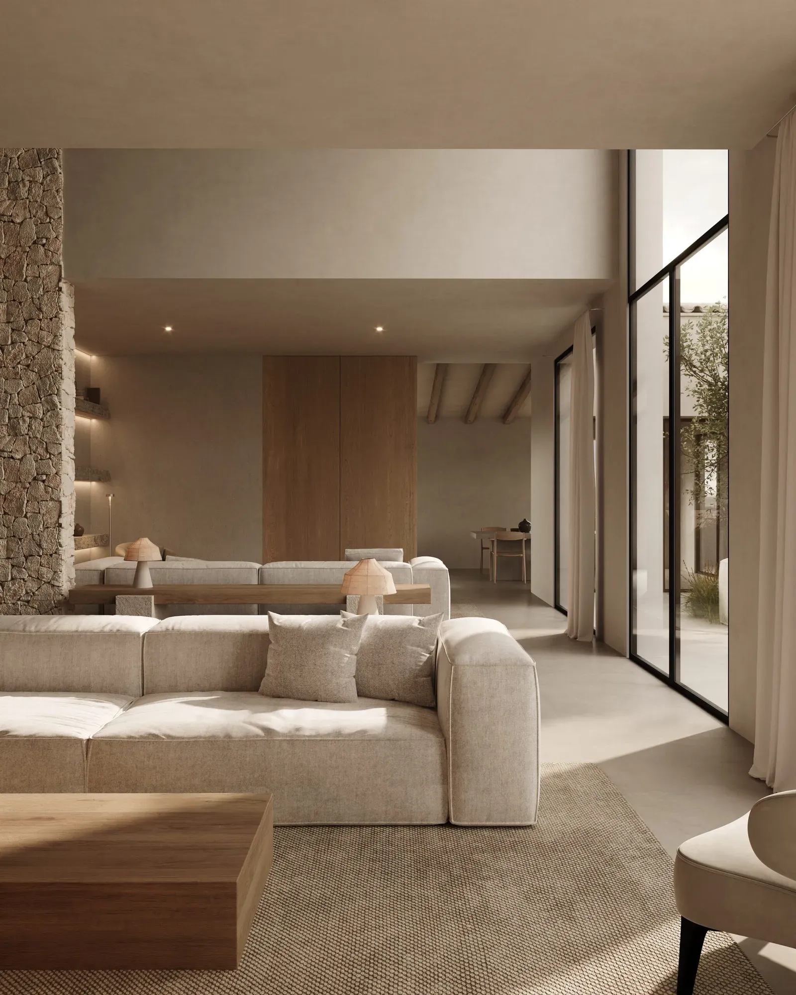 Living room in warm beige tones with a linen sofa, rough stone wall and floor-to-ceiling windows onto a courtyard