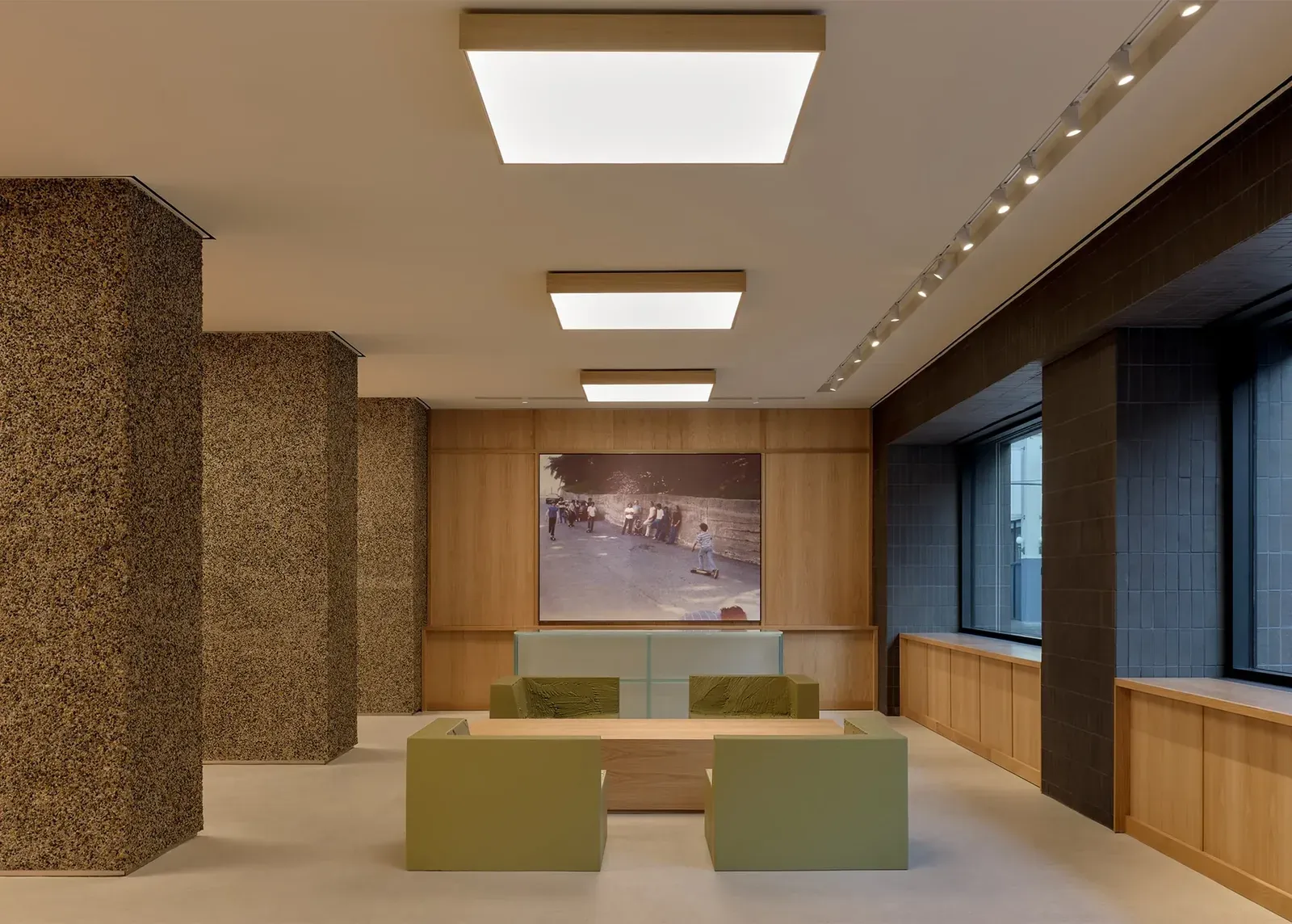 Lounge in the new Stüssy store: green block armchairs around an oak table, a large photo of kids skateboarding behind