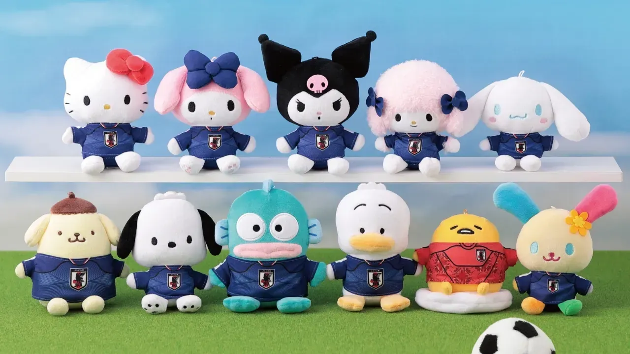 Hello Kitty and ten other plush characters in Japan national team shirts, lined up like a team on a shelf and grass
