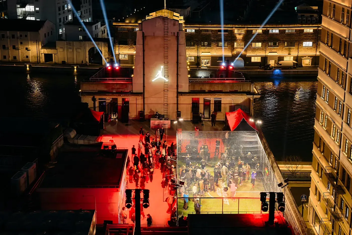 Hypebeast Cup rooftop at night: a netted pitch by a river, a crowd in red light and a Jordan Jumpman on the tower