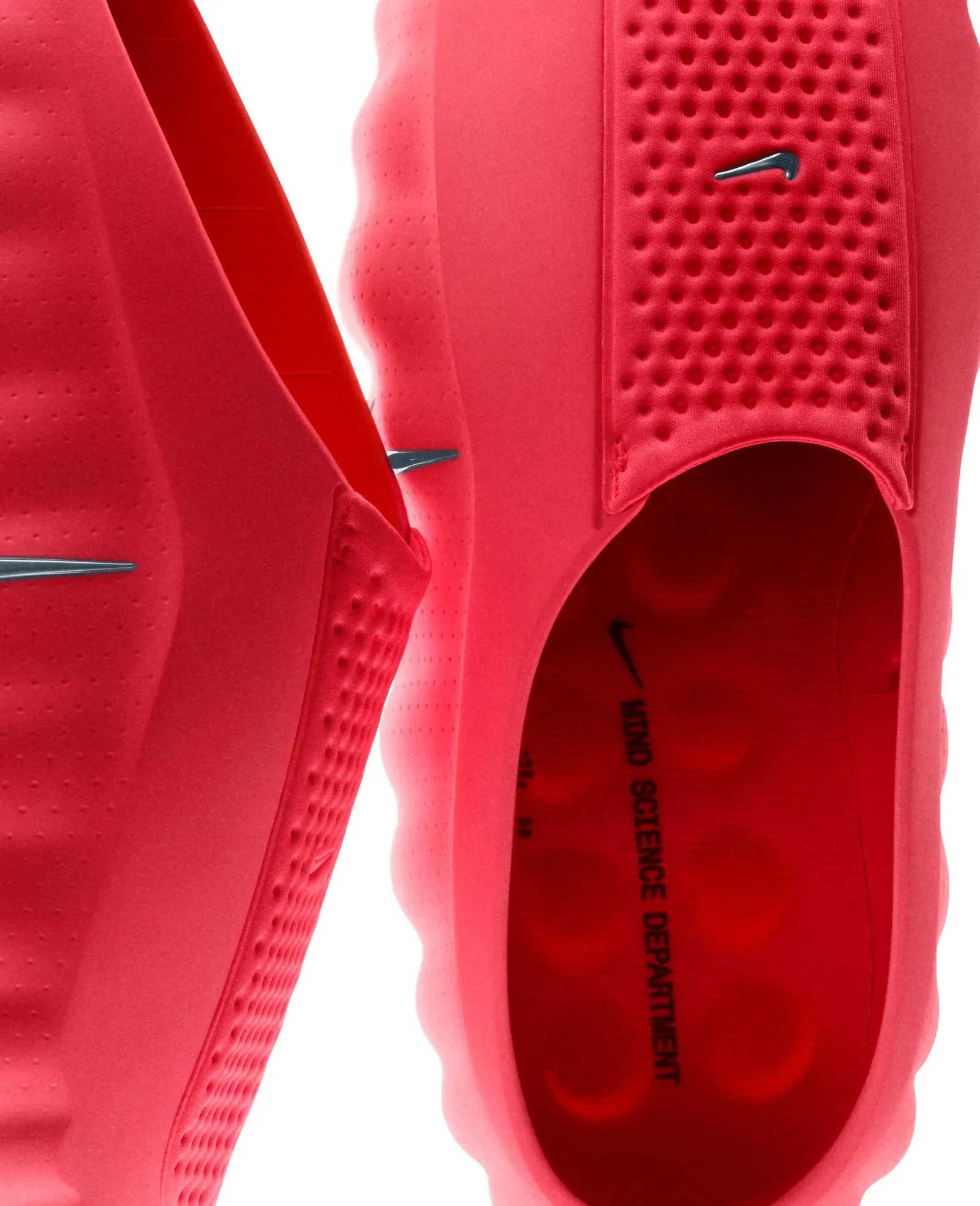 Close-up of two red Nike Mind shoes with silver swooshes, one insole printed Mind Science Department