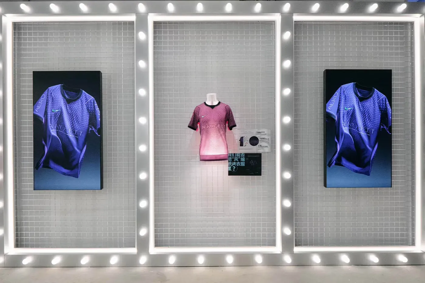 Nike Aero-FIT display: a pink shirt on a bust between two screens showing the shirt in purple, in bulb-lit frames