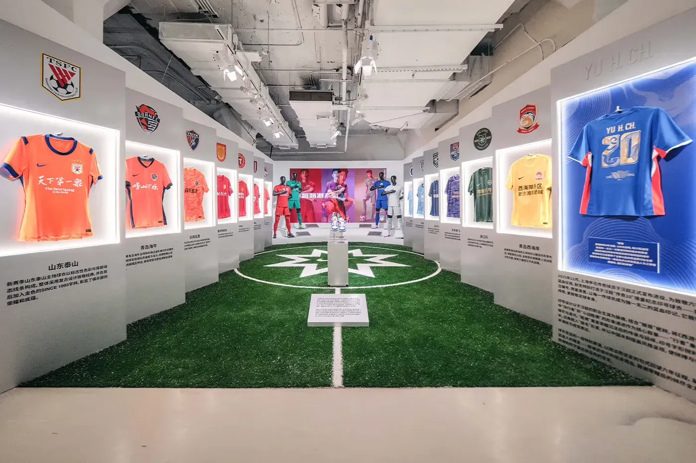 Exhibition corridor of Chinese club shirts in lit frames along a strip of turf with a star in the centre circle
