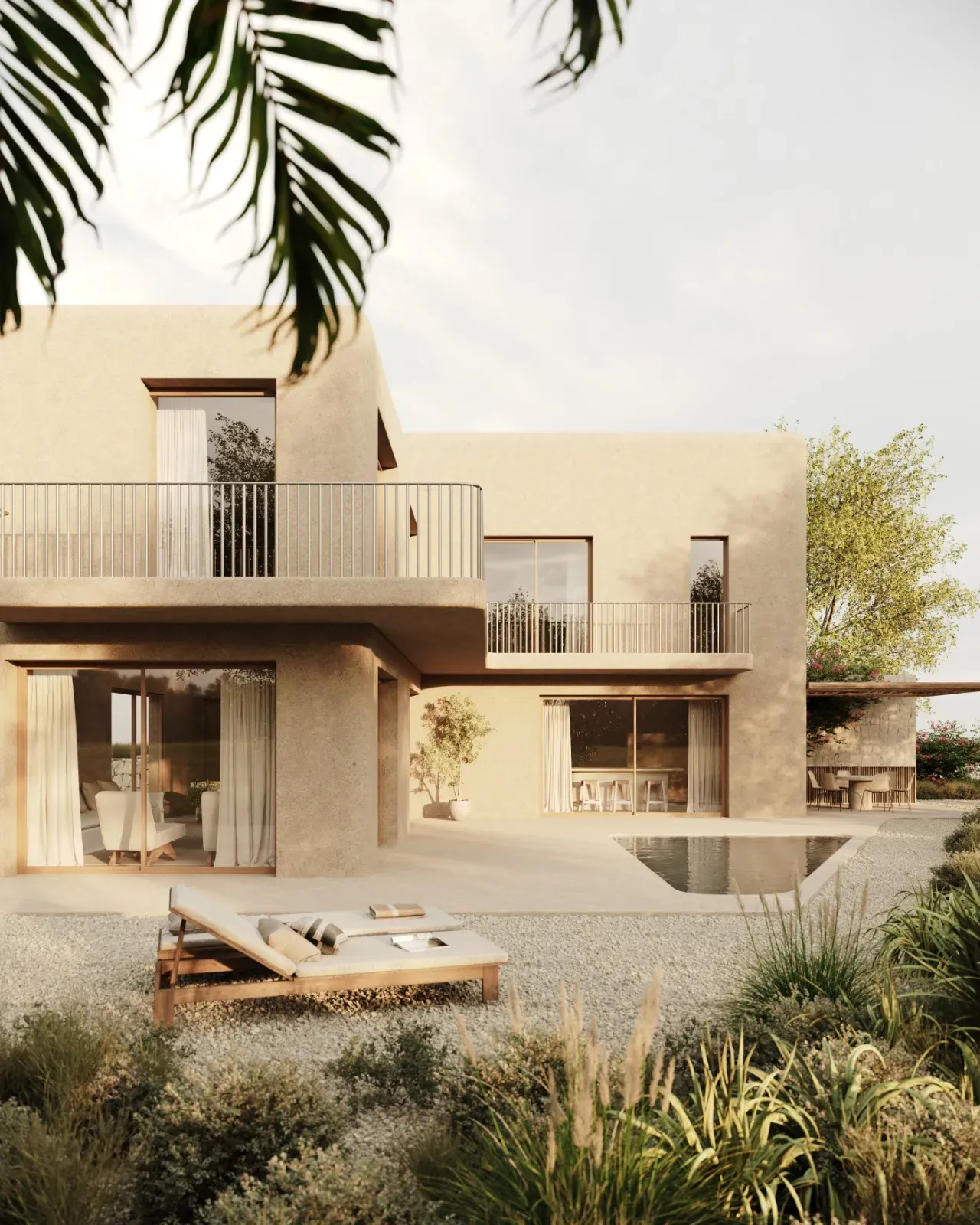 Two-storey plaster house with rounded balconies, a small pool, two sun loungers on gravel and palm leaves in front
