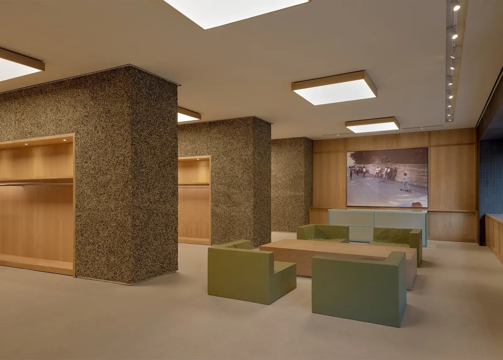 Wider view of the lounge, with oak niches in the pebble-clad pillars, green armchairs and the large skateboarding photo