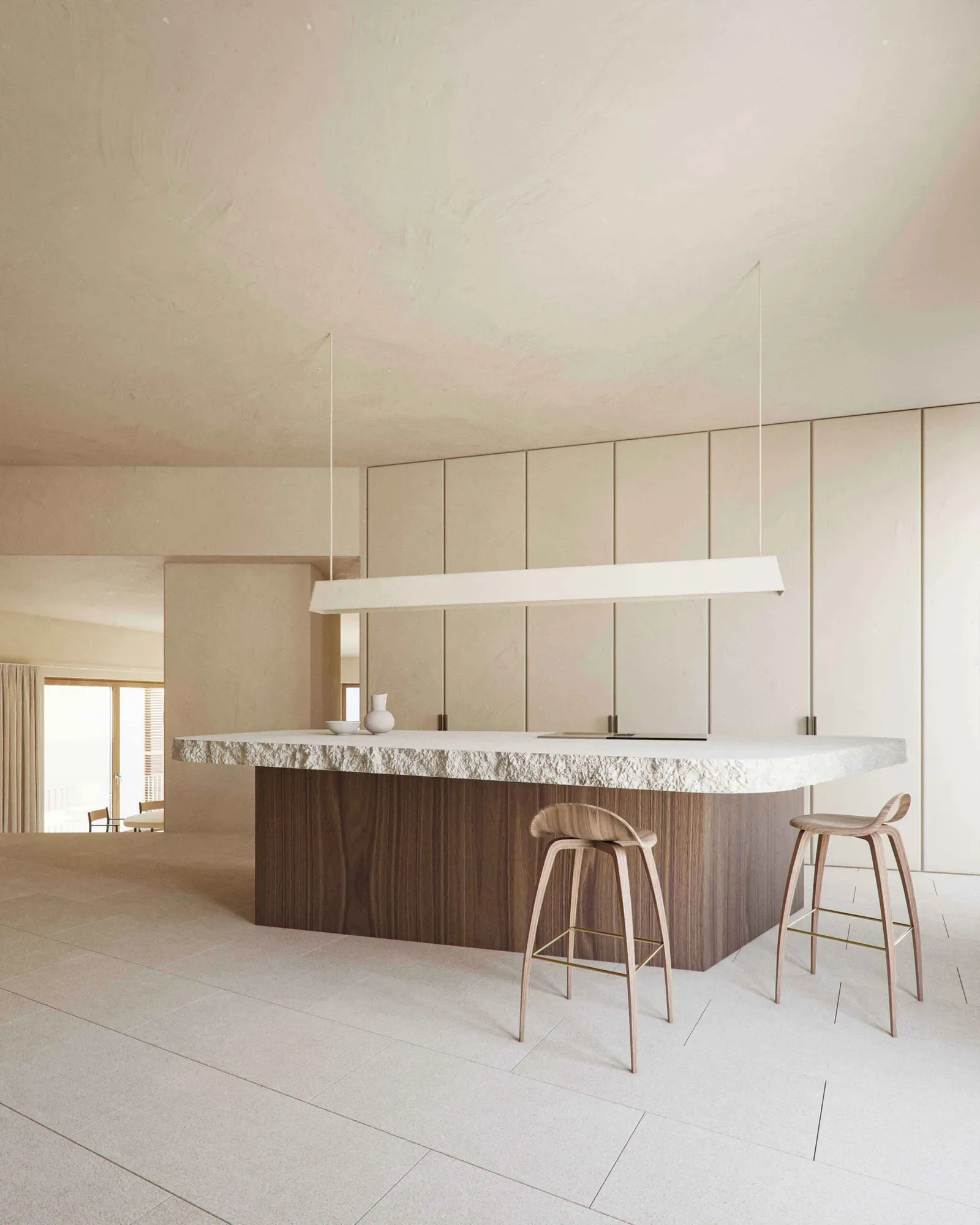 Kitchen island with a rough-edged stone top on a walnut base, two wooden bar stools and a long white pendant light