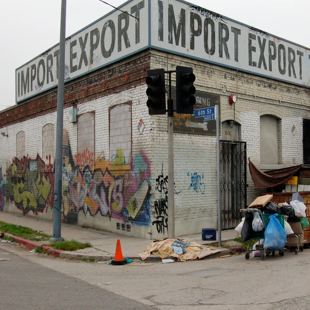 A corner building painted Import Export Toys & General Merchandise, graffiti along its wall.