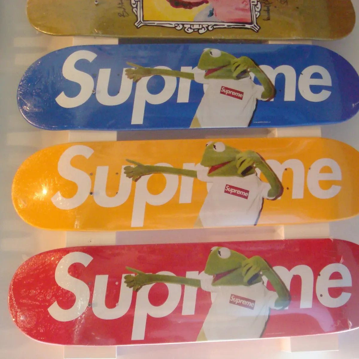 Supreme skateboard decks with Kermit in blue, yellow and red.
