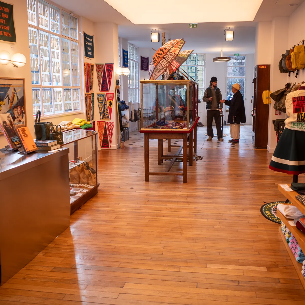 A long wooden-floored shop with clothes and objects on display.