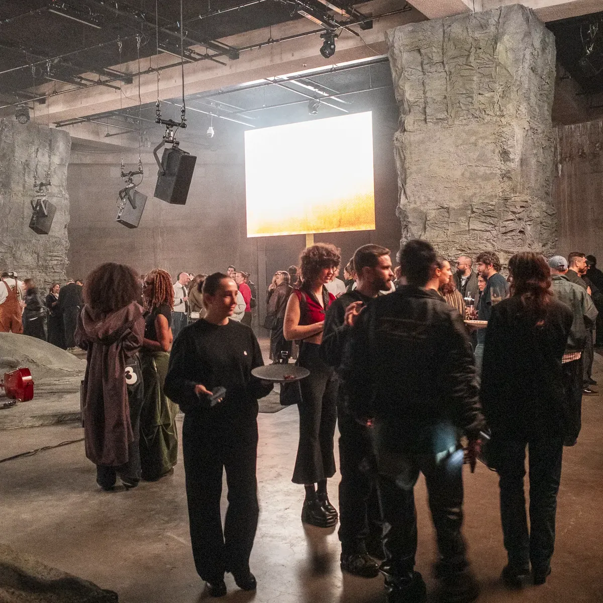 Guests crowding the hall in front of a glowing screen.
